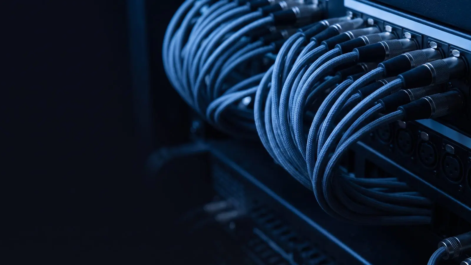 A dense patch bay of woven cables converging in blue light.
