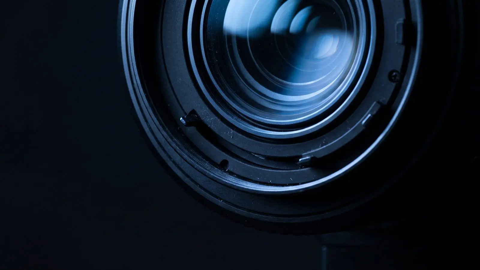Extreme close-up of a small camera lens with a blue reflection.