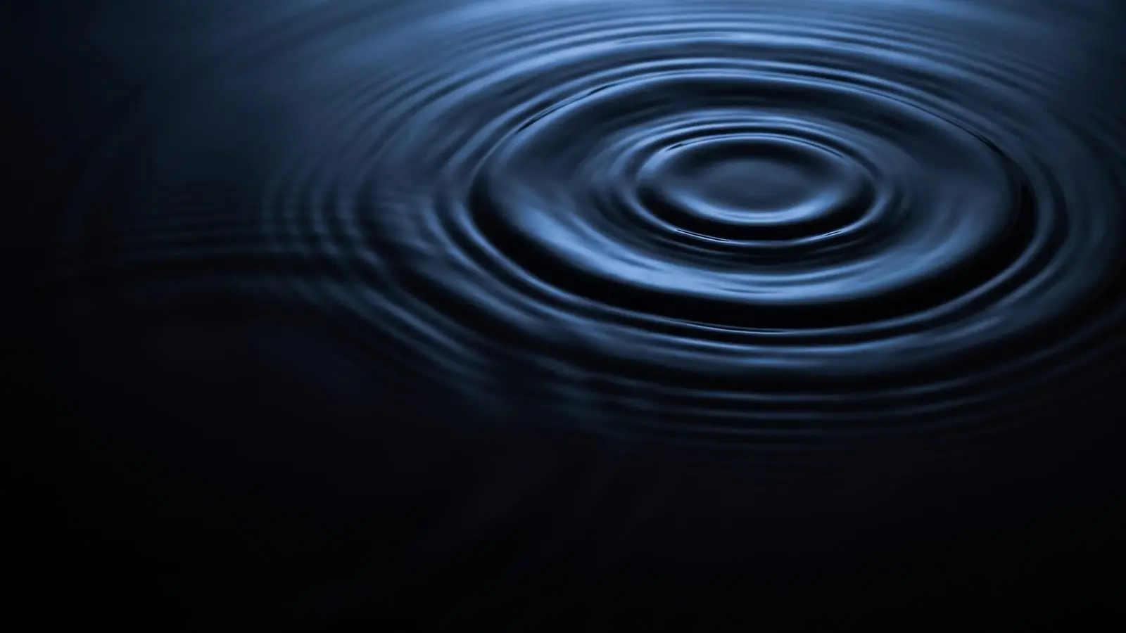 Concentric ripples spreading across dark water, seen from above.