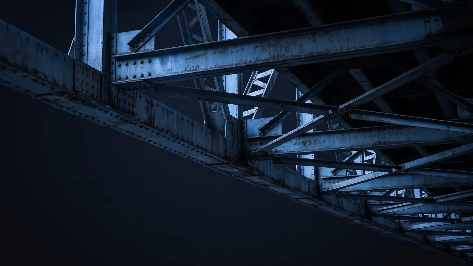 The repeating steel geometry of a bridge truss seen from below.