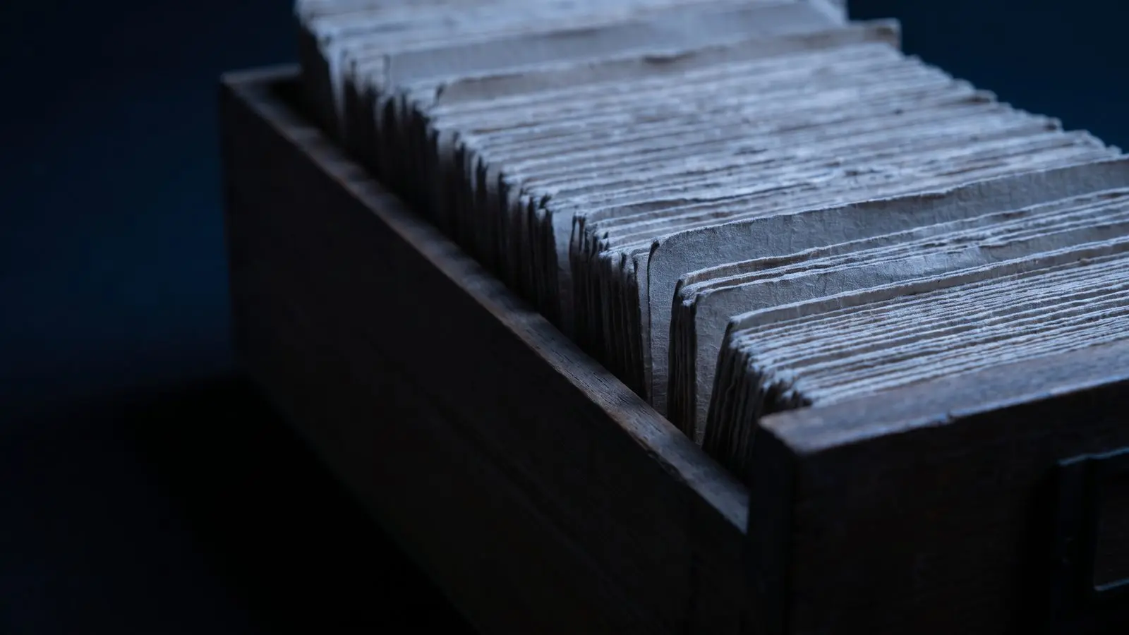 An open drawer of tightly packed paper index cards.